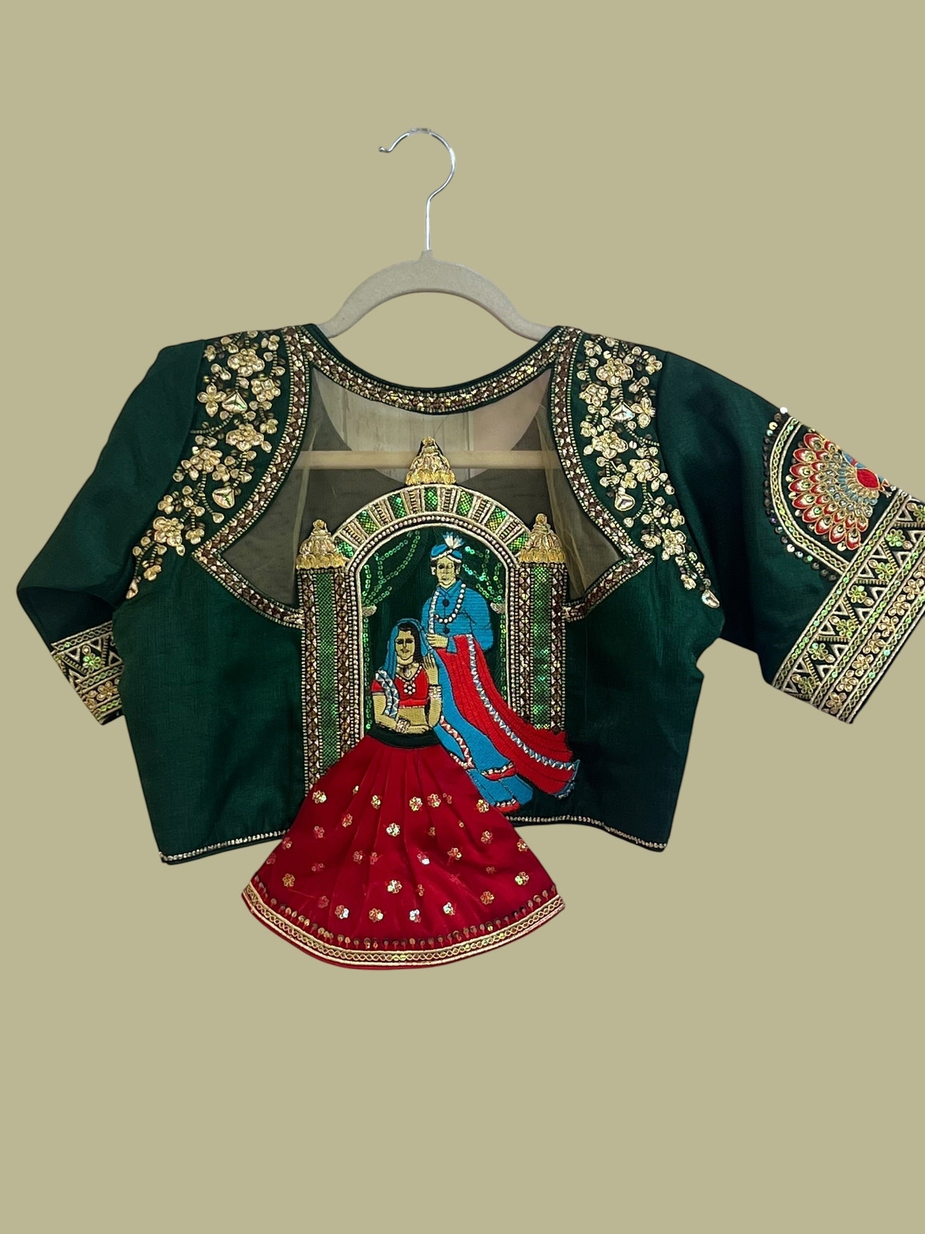 House Of Indian Wedding Attire deep green blouse with gold embroidery, sequins, and royal couple motif on sheer back panel.