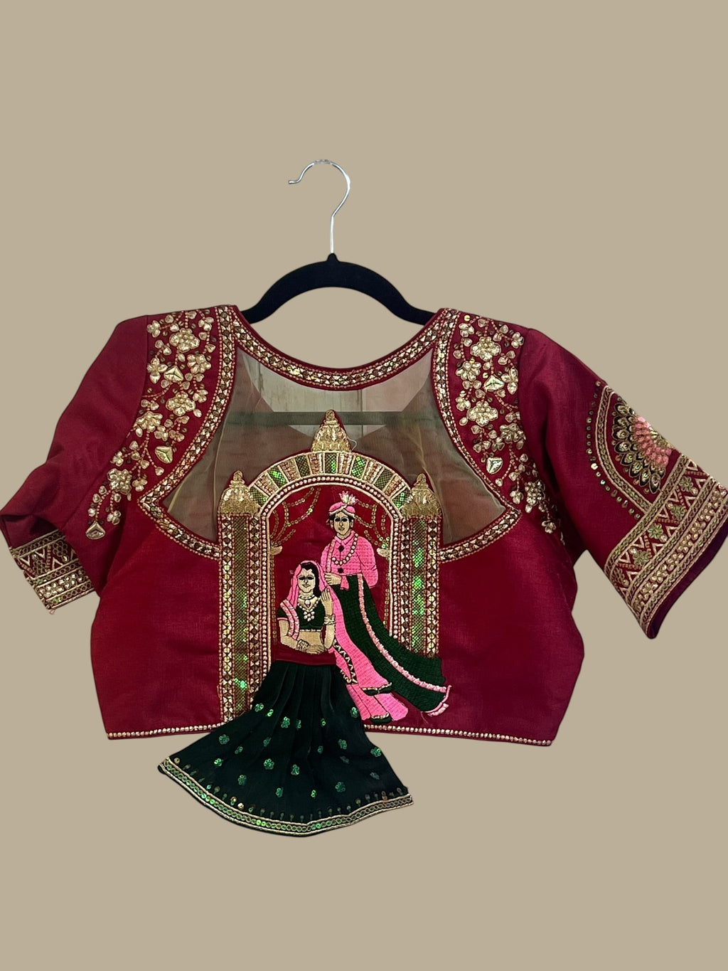 House Of Indian Wedding Attire maroon silk-like blouse with gold embroidery and sheer yoke, paired with a dark green skirt.