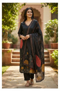 Kurti Connection USA black kurti set with abstract floral print, V-neck, full sleeves, matching dupatta, and black pants. Model is outdoors.